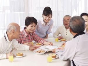 介護職員と入居者が一緒に食事をしている食堂の風景