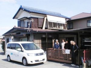 施設の玄関前に停車した送迎車と建物外観